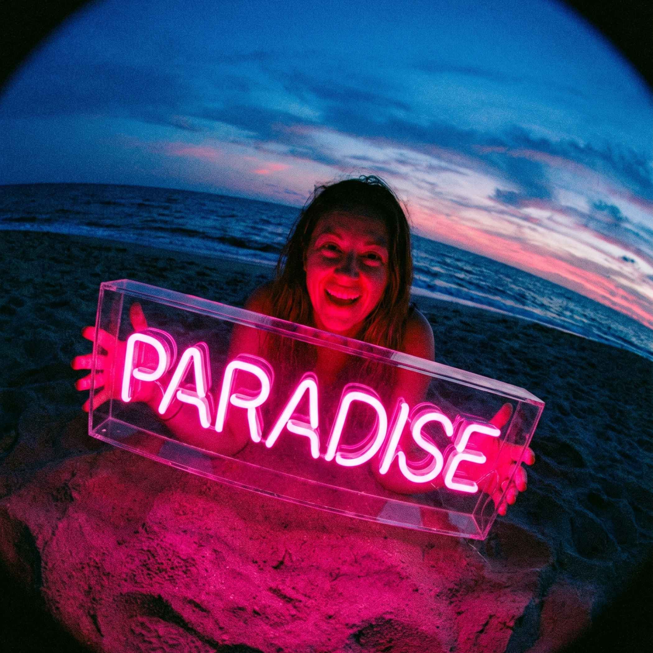 Paradise pink LED neon sign in acrylic box held at beach sunset — Vertical Design DXB Dubai
